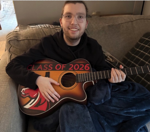 Alex playing a guitar decorated with the words Class of 2026